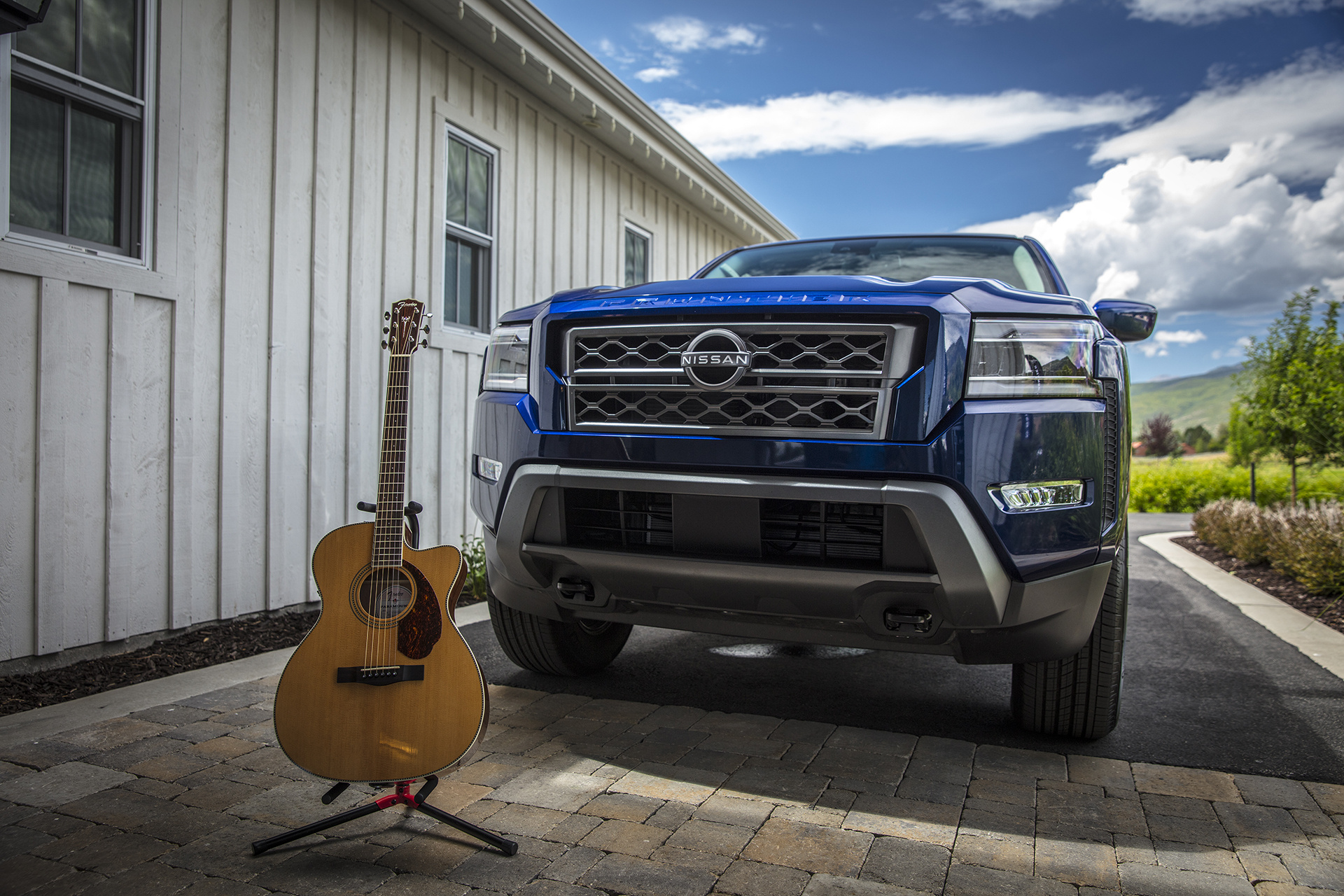 Exterior shot of a Nissan Frontier next to a Fender acoustic guitar