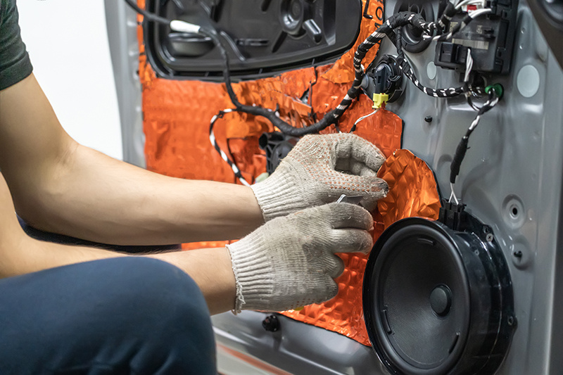 factory worker installing noise management components into a vehicle door